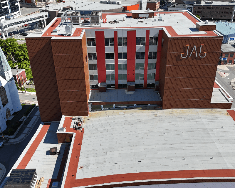 Aerial view of a multi-story building with _JAG_ on the facade, featuring red and white vertical stripes Aerial view of a multi-story building with "JAG" on the facade, featuring red and white vertical stripes